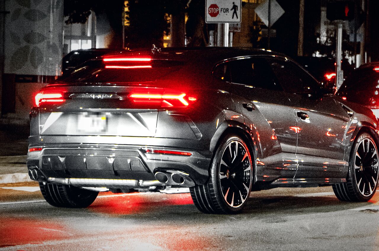 Traseira de um Lamborghini Urus cinza à noite, com as lanternas acesas